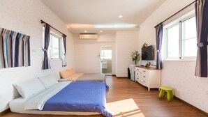 Un dormitorio con dos camas, televisión, escritorio y un taburete pequeño.