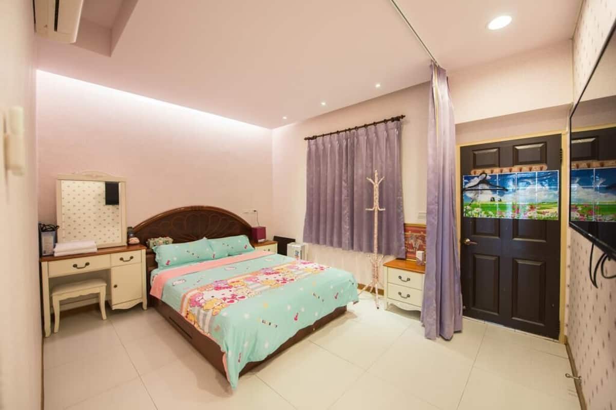 A bedroom with a bed, a desk, a wardrobe, and a door with a view.