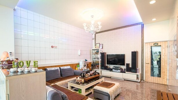 Una sala de estar moderna con un sofá, una mesa de centro, un televisor y una araña.