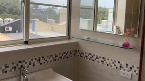 Un baño con ventana, lavamanos y espejo.