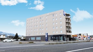 A multi-story hotel with a flat facade, a parking sign, and a clear sky.
