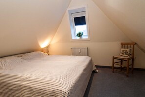 A bedroom with a bed, a chair, a window, and a radiator.