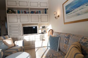 A living room with a sofa, a television, and a bookshelf.