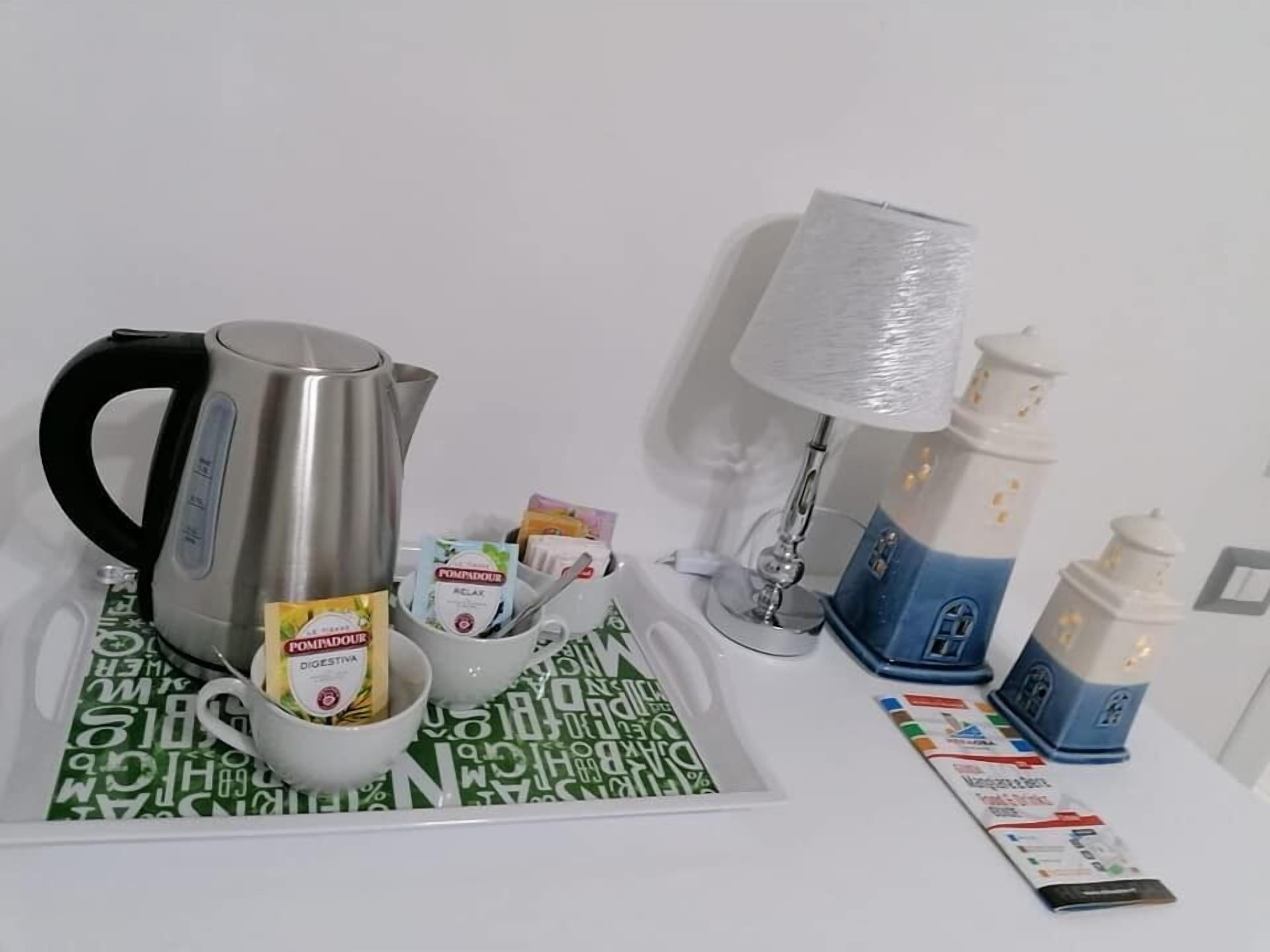 A breakfast setup with a kettle, cups, and a tray of food items.