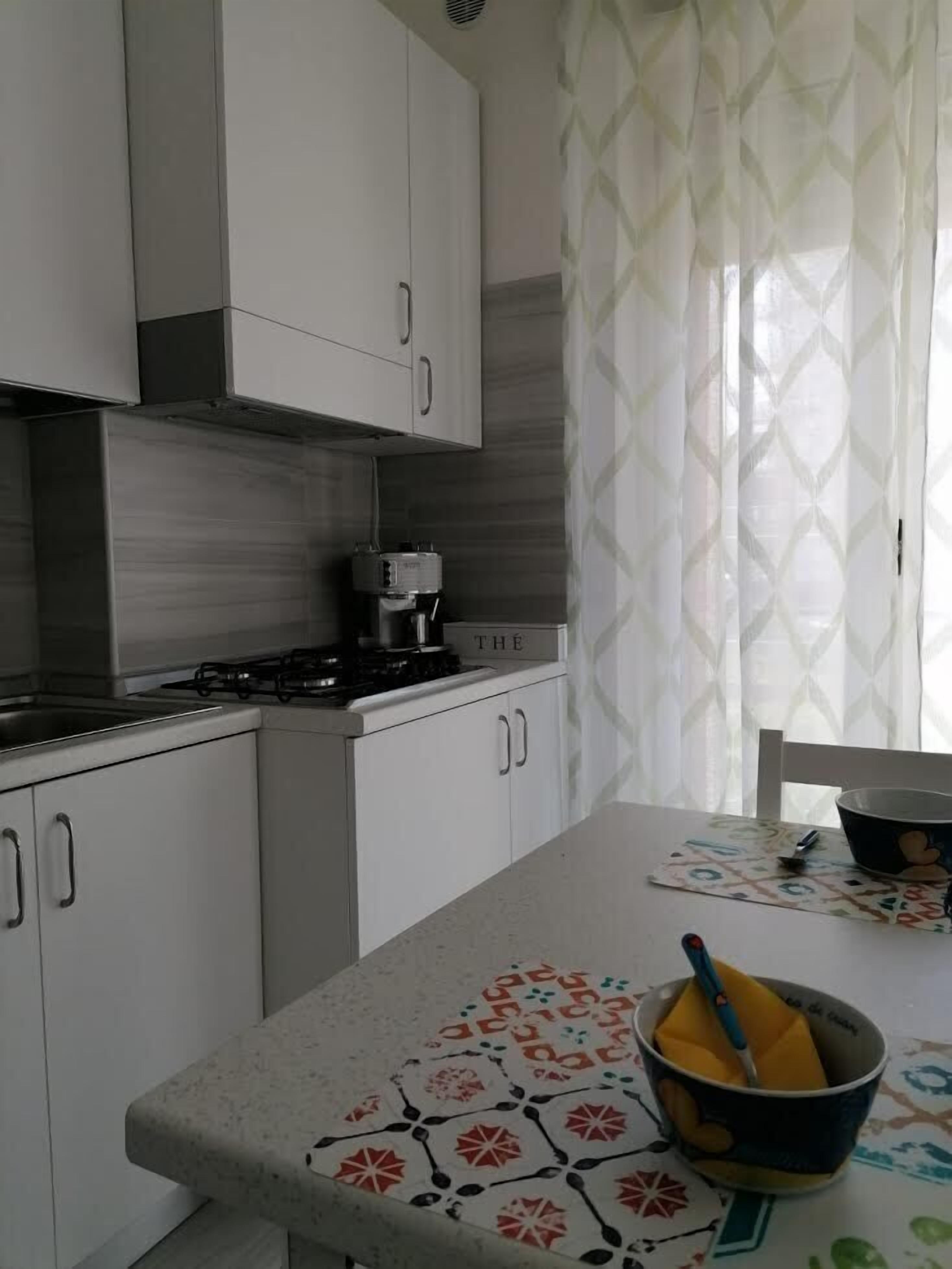 A kitchen with white cabinets, a gas stove, and a coffee maker.