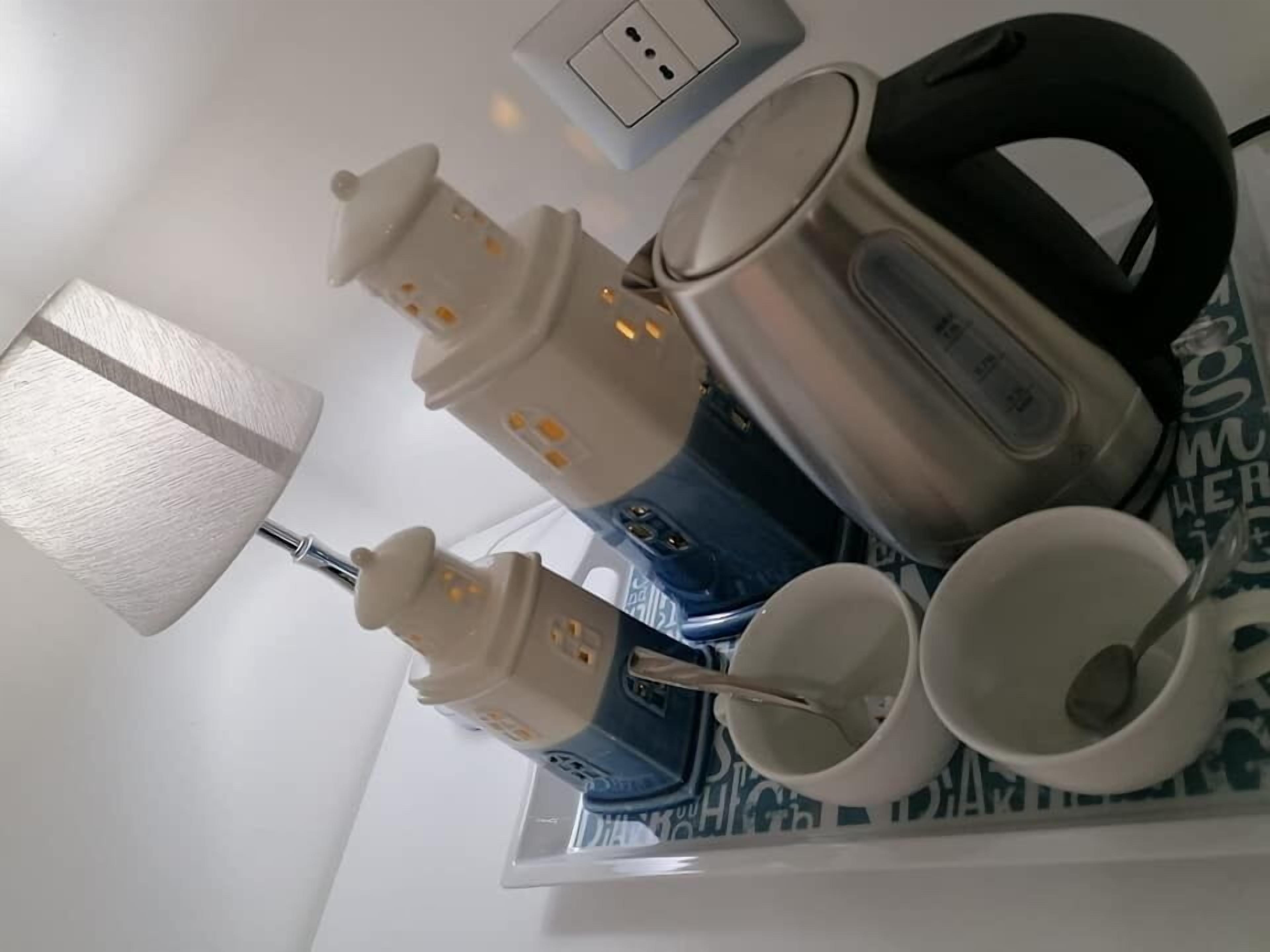 Un coin cuisine équipé d’une machine à café, de tasses et d’une bouilloire.