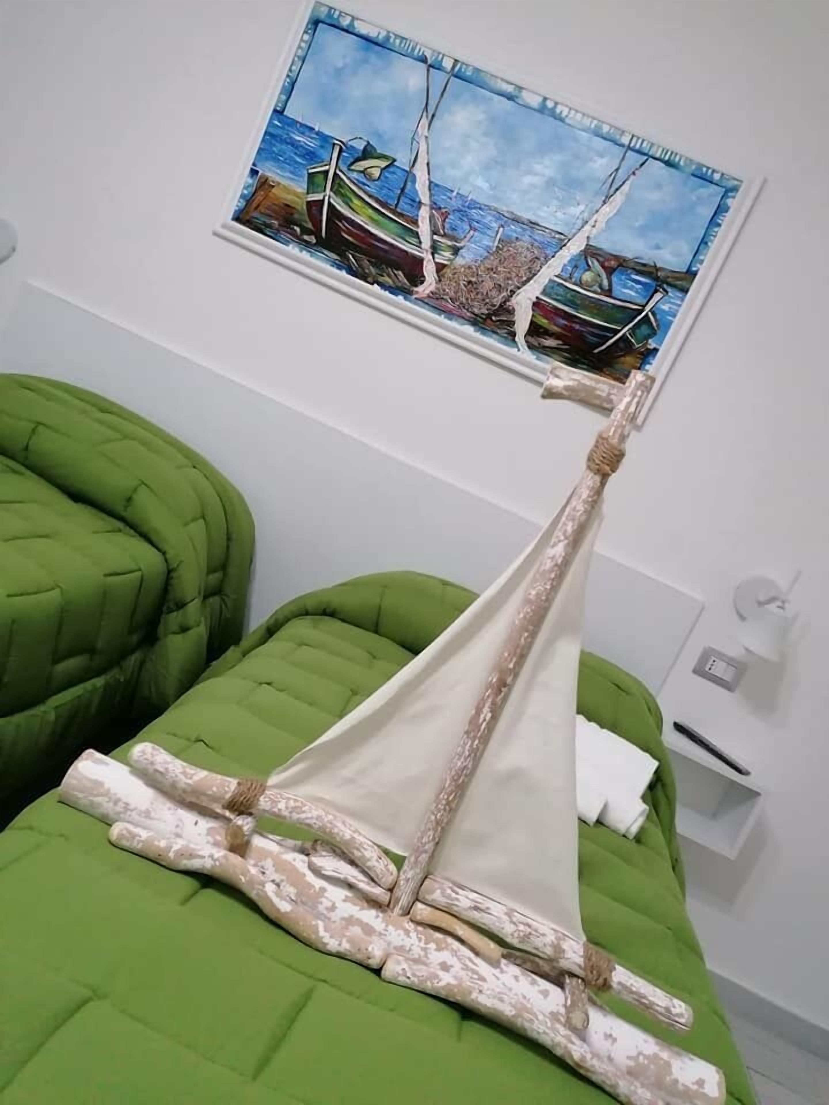 A bed with a sailboat painting and a rope decoration.