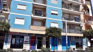 A multi-story building with balconies, a pizzeria on the ground floor, and a closed shuttered shop. - B&B Audafra (Crotone)