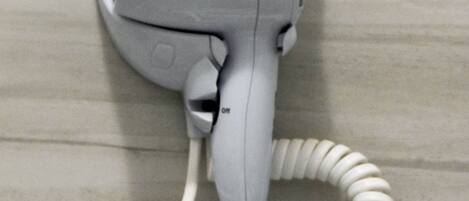 A white hair dryer mounted on a tiled wall.