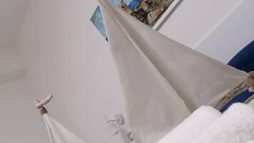 Um modelo de veleiro sobre uma cama, com uma pintura de paisagem ao fundo.