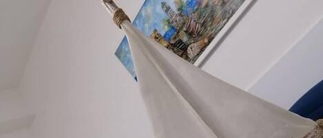 A sailboat model on a bed with a painting of a landscape in the background.