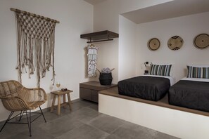 A modern bedroom with a bed, two bedside tables, a chair, a hanging macrame piece, and wall decor.