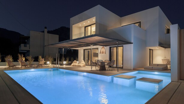 Una casa moderna con piscina, mobiliario exterior y un porche cubierto.