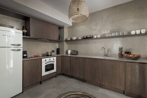 A modern kitchen with a white refrigerator, oven, and sink, wooden cabinets, and a hanging light fixture.