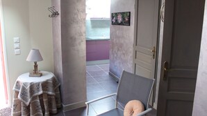 Un couloir avec une chaise, une table avec une lampe et une porte donnant sur une pièce.