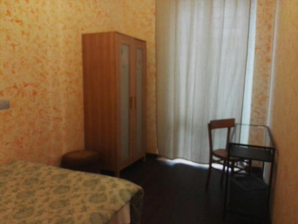Una habitación con una cama, un armario de madera, una silla y una ventana con cortinas.