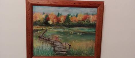 Una pintura de un puente de madera sobre un cuerpo de agua, con árboles al fondo.