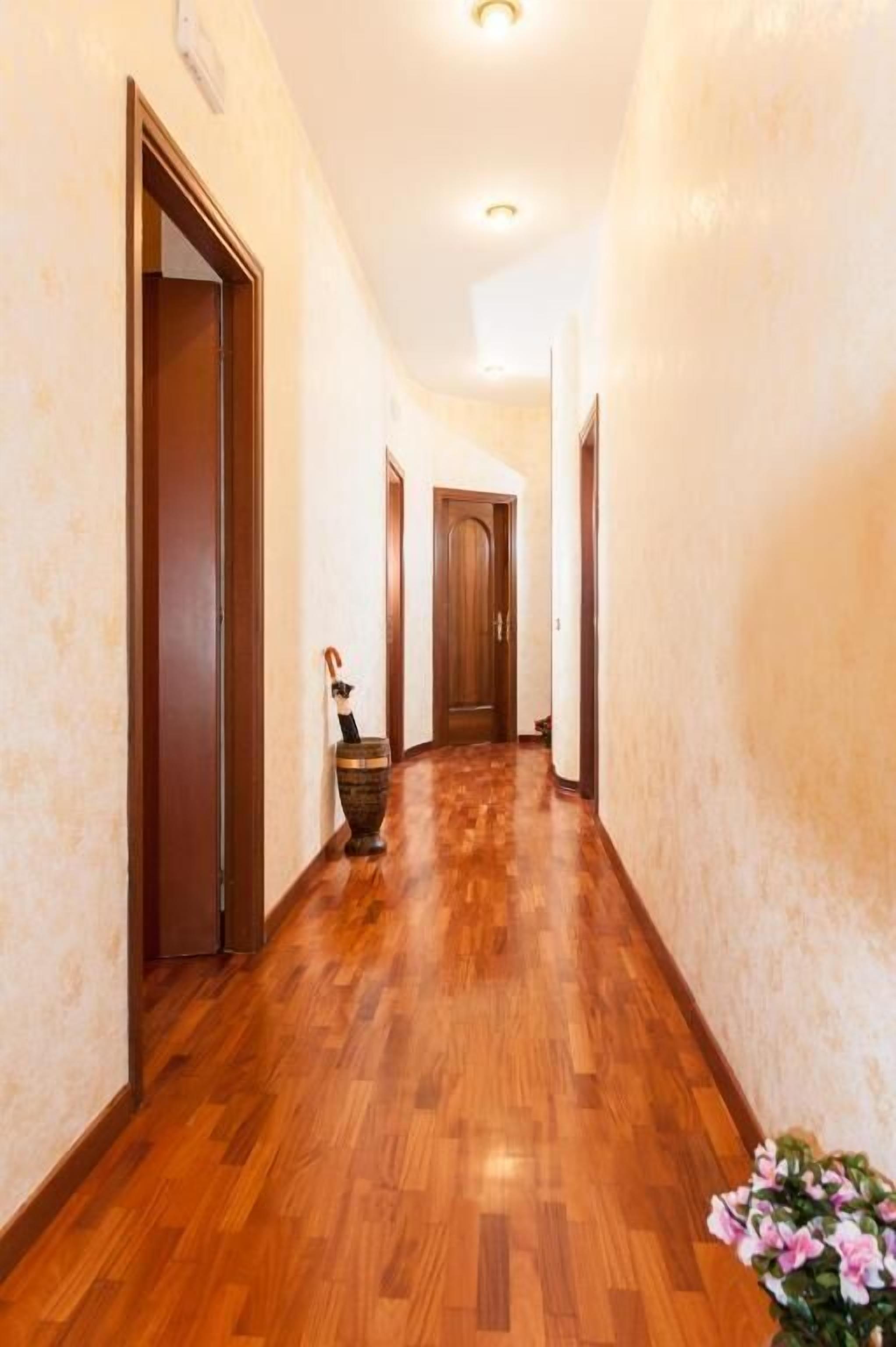 Un pasillo con suelo de madera y puertas a ambos lados.