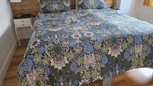 A bed with a floral-patterned bedspread, two bedside tables with lamps, and a wooden headboard. - Willow Cottage,, Experience the North Downs in fully accessible comfort. (maidstone)
