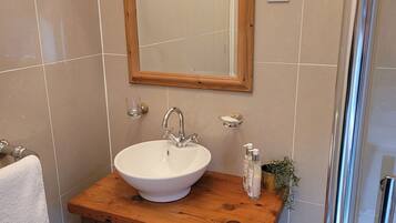 A bathroom with a wooden vanity, white sink, and a mirror above it.