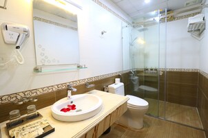 Un baño moderno con ducha de vidrio, lavabo blanco con recipiente de vidrio y un inodoro.