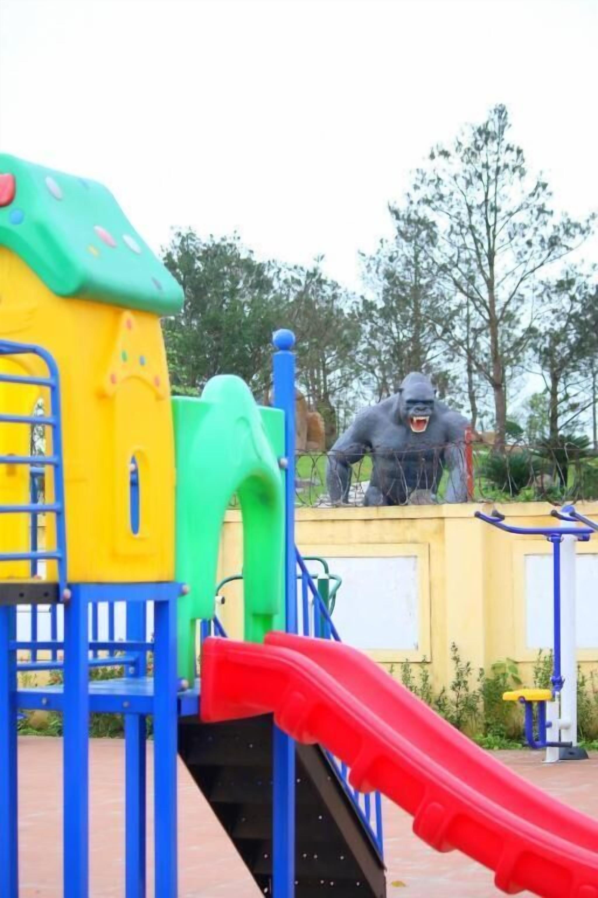 A playground with a slide, climbing structures, and a gorilla statue.