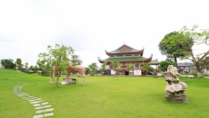 A traditional building with a multi-tiered roof, a stone pathway, and two giraffes in a grassy area. - Resort Huu Bang (Hai Phong)