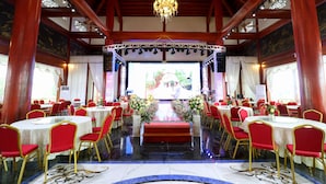 A banquet hall with round tables, red chairs, and a central stage with a red carpet. - Resort Huu Bang (Hai Phong)