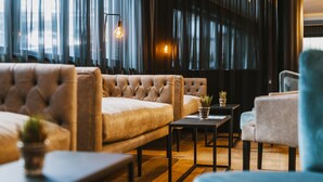A modern living room with a tufted sofa, a small table with a plant, and a blue armchair. - The House Zell am See (Zell am See)