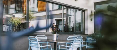 An outdoor seating area with a table and chairs in front of a building with a sign that reads "The House."