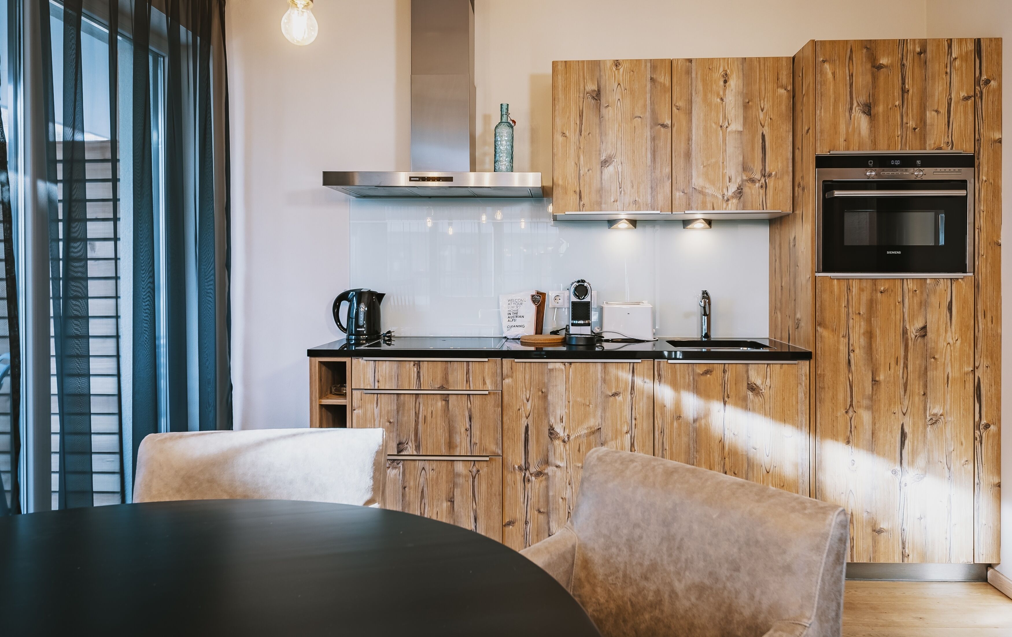 Eine moderne Küche mit Holzschränken, einer schwarzen Arbeitsplatte und einem eingebauten Ofen.
