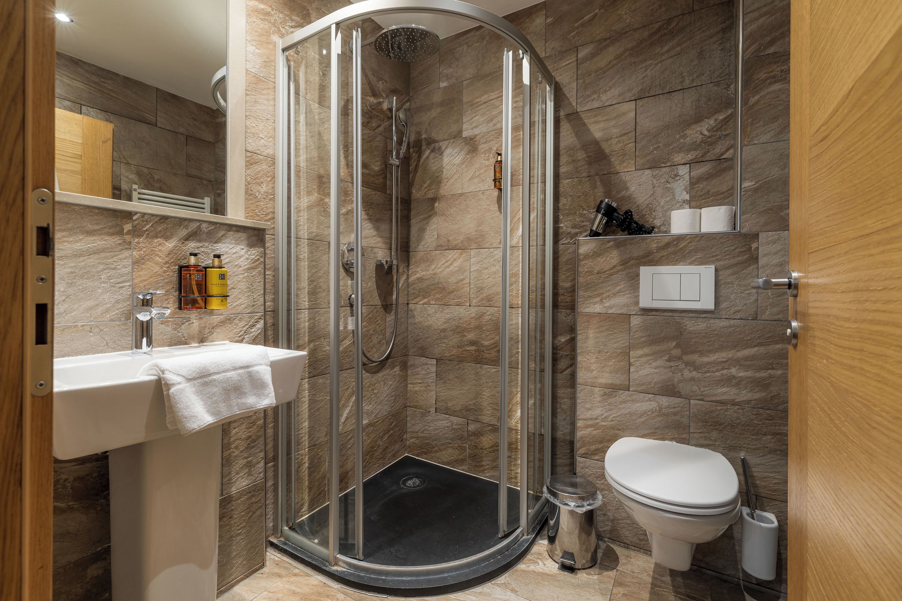 A modern bathroom with a glass-enclosed shower, a sink, and a toilet.