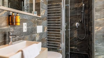A modern bathroom with a glass-enclosed shower, a vanity with a sink and mirror, and a toilet.