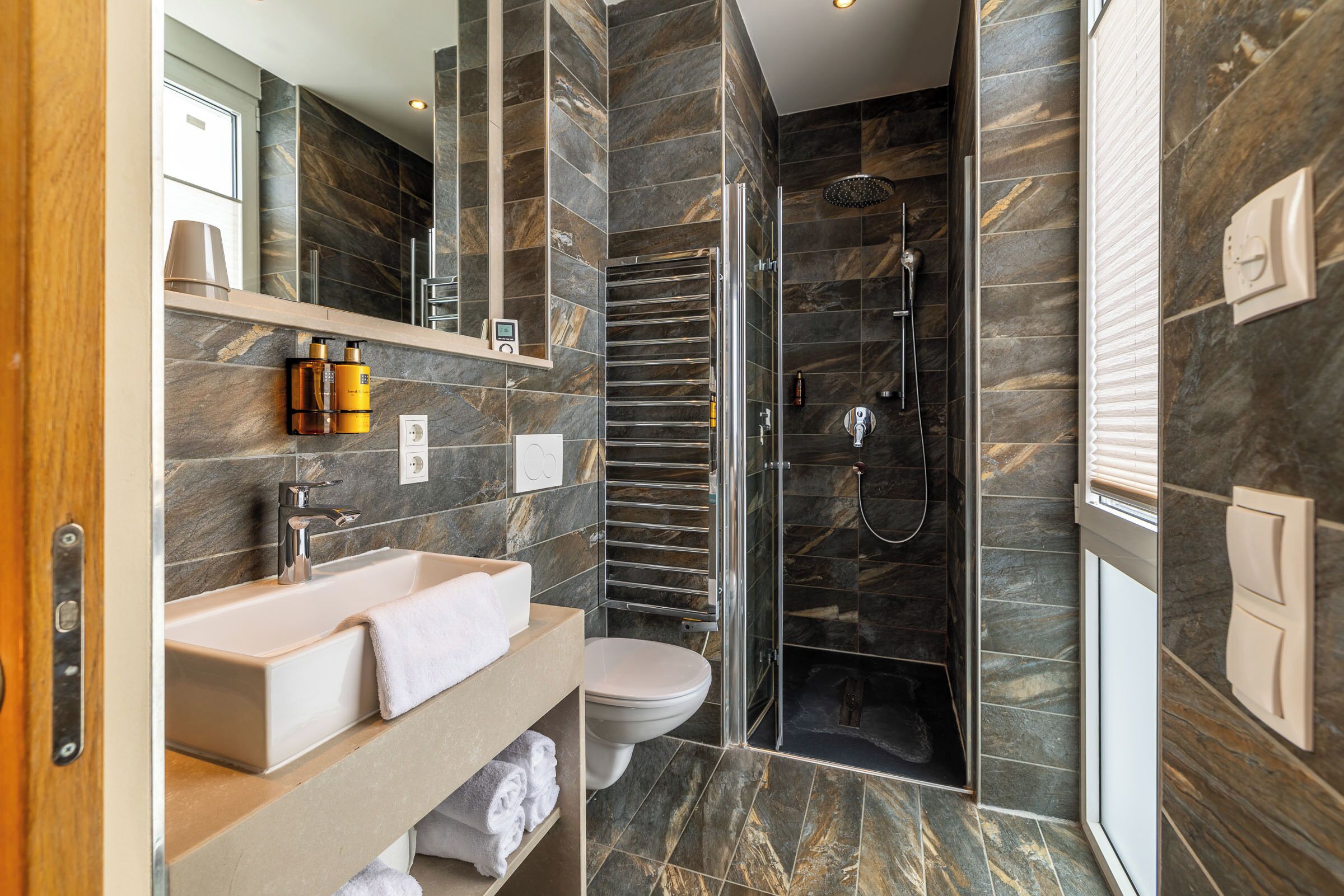A modern bathroom with a large mirror, a sink, a toilet, and a shower area.