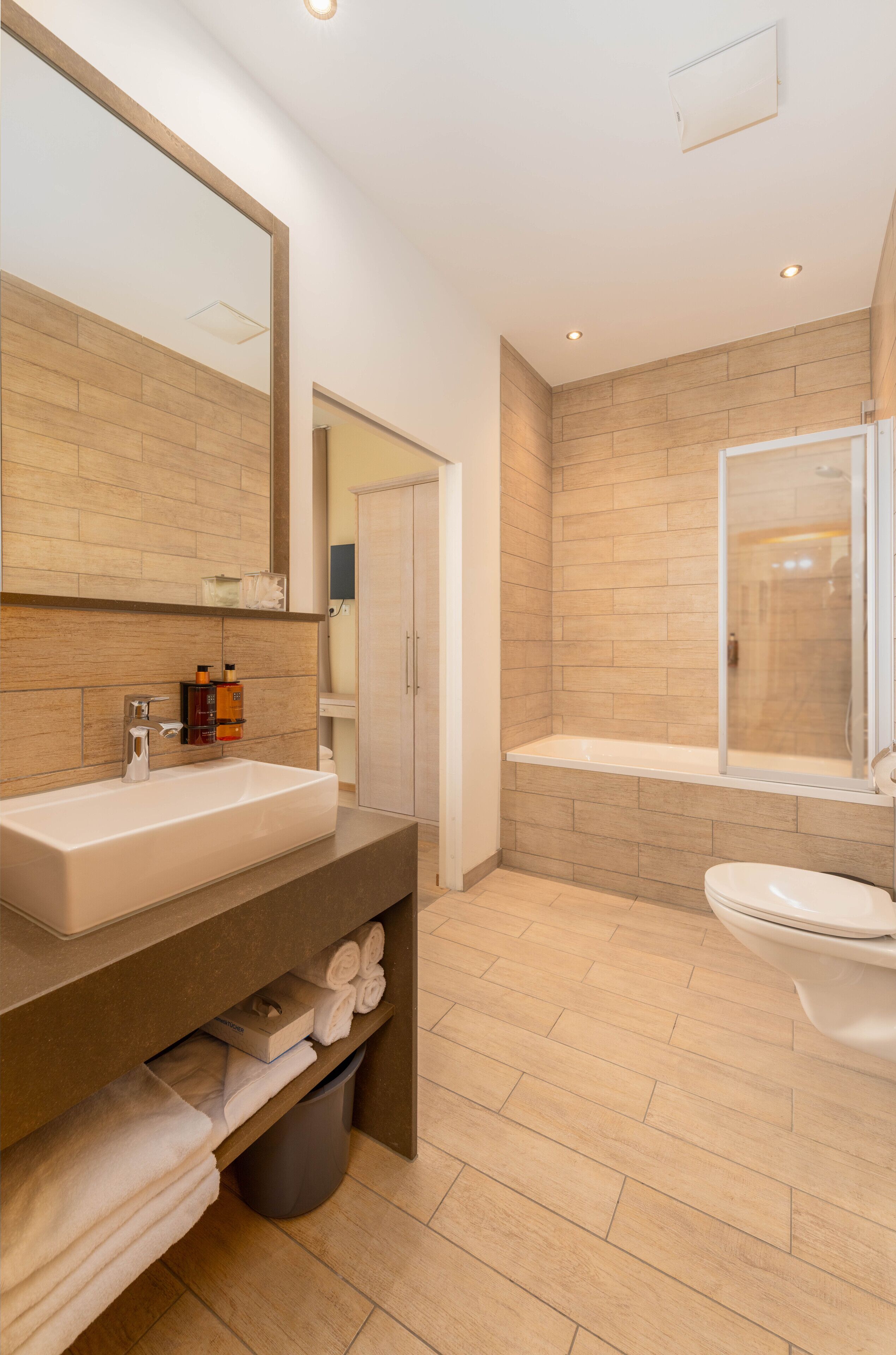 Une salle de bain moderne avec un grand lavabo, un miroir et un espace douche.