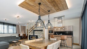 A modern kitchen with a central island, wooden ceiling, and pendant lighting. - The House Zell am See (Zell am See)