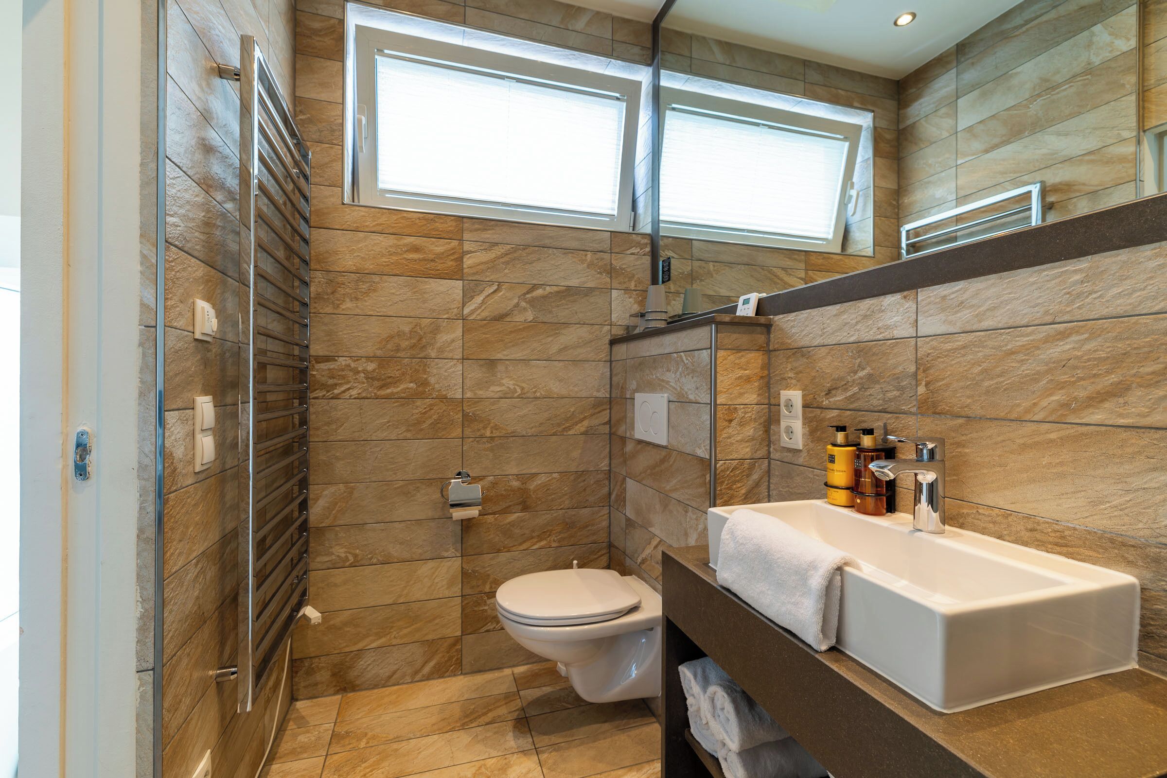 Un baño moderno con ducha, inodoro y un lavamanos grande.