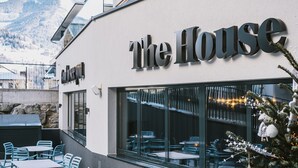 A building with a sign reading "The House" and a view of outdoor seating with tables and chairs. - The House Zell am See (Zell am See)