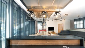 Een moderne keuken met een groot eiland, hanglampen en uitzicht op de woonkamer.