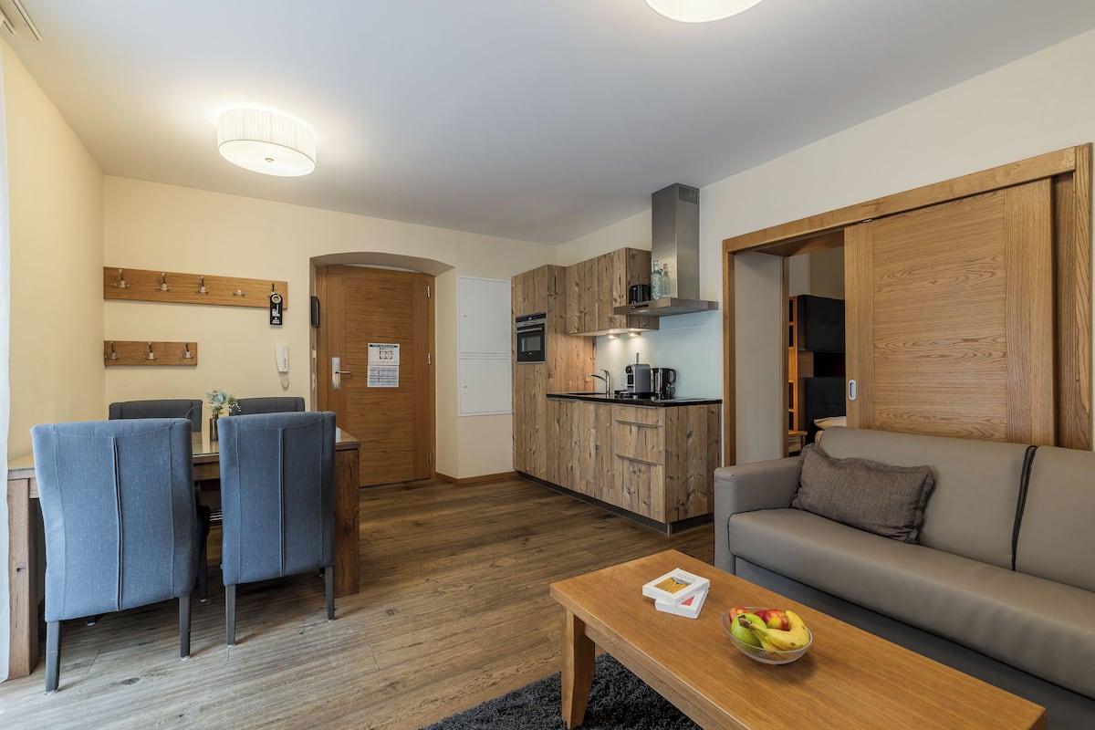 A compact living space with a dining area, kitchenette, and a sofa.