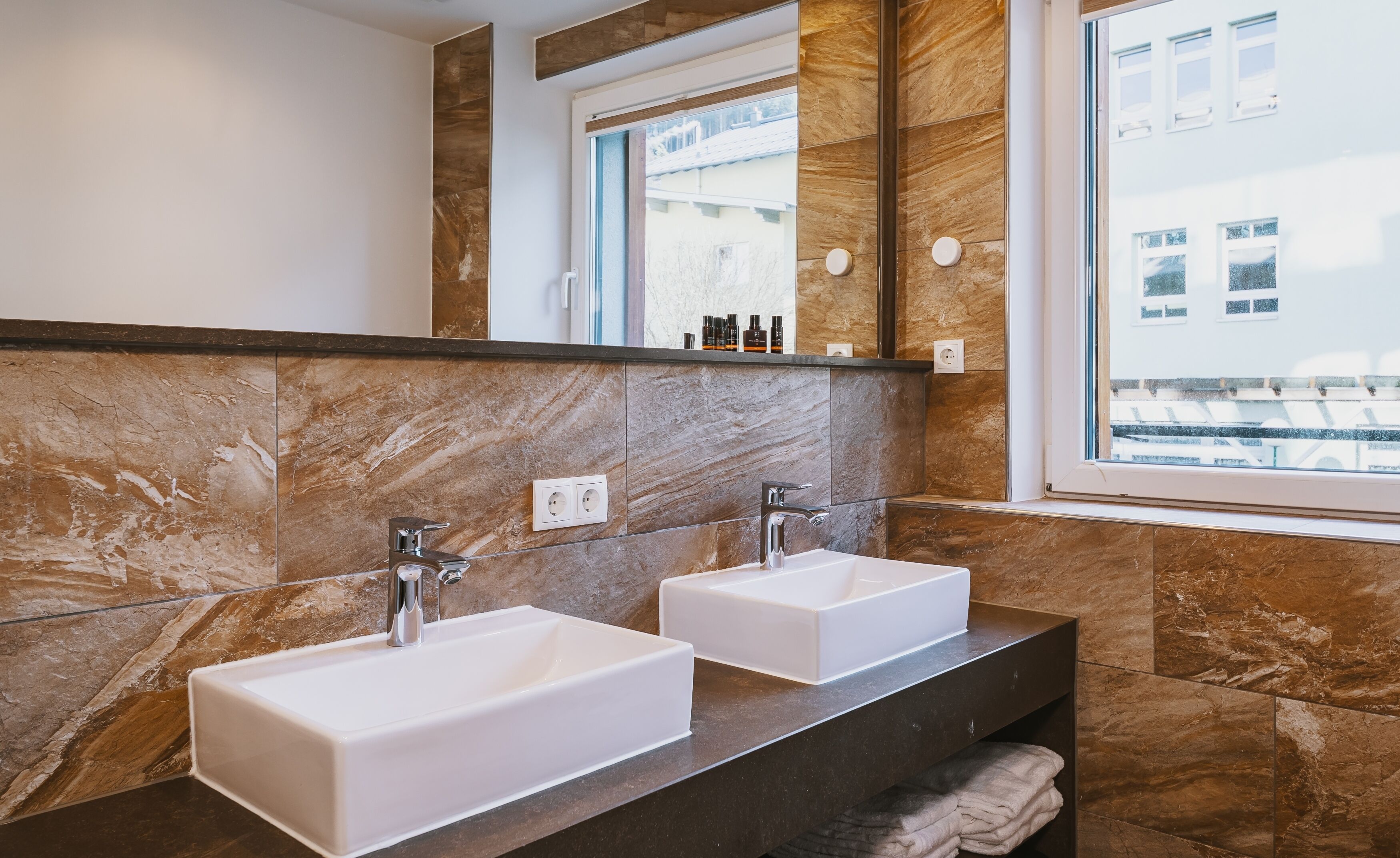 A bathroom with two white sinks, a dark countertop, and a large mirror.