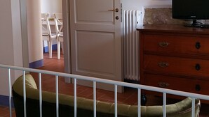 Een kamer met een bed, een dressoir, een televisie en een deur naar een andere kamer.