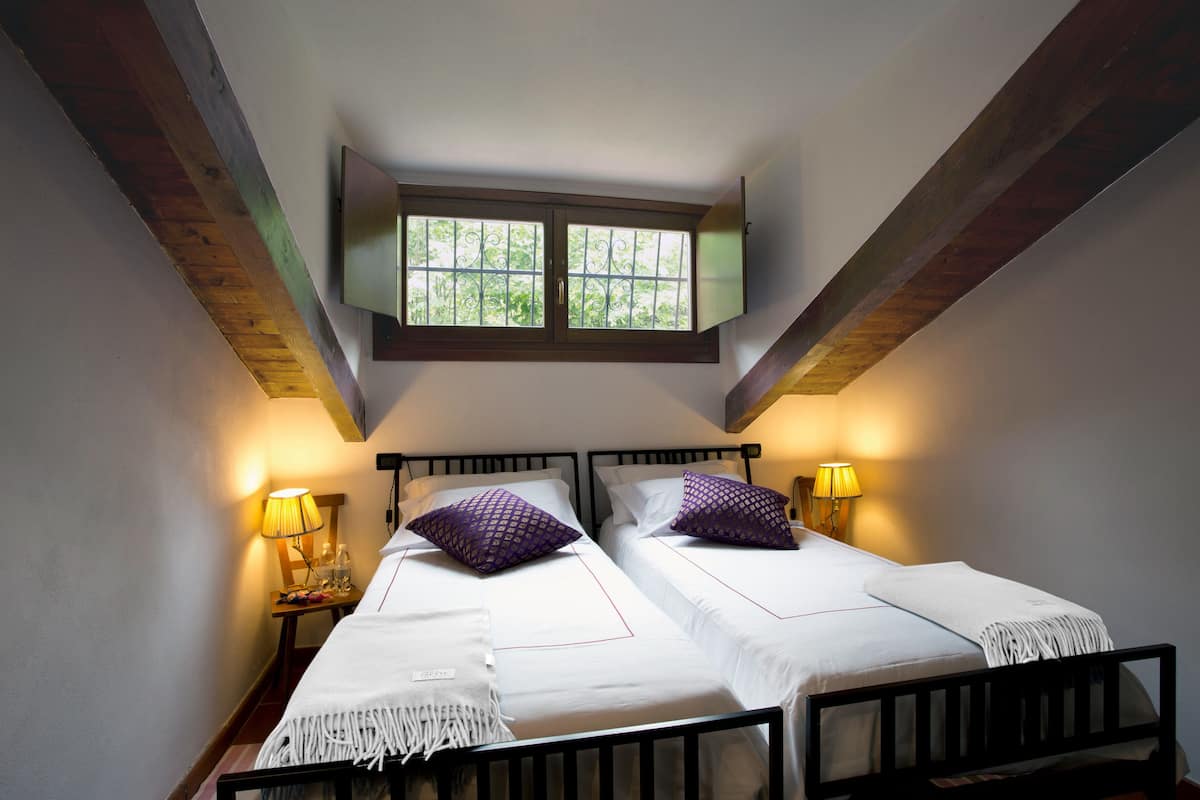 Een tweepersoonskamer met twee bedden, een raam en een houten plafond.