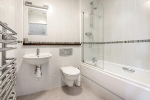 Ein modernes Badezimmer mit Waschbecken, Toilette und Badewanne, alles in Weiß.