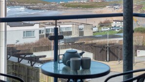 Un balcon avec une table et des chaises, donnant sur une plage et des immeubles.