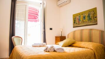 Una camera d'albergo con un letto, una sedia, un quadro e un condizionatore d'aria.