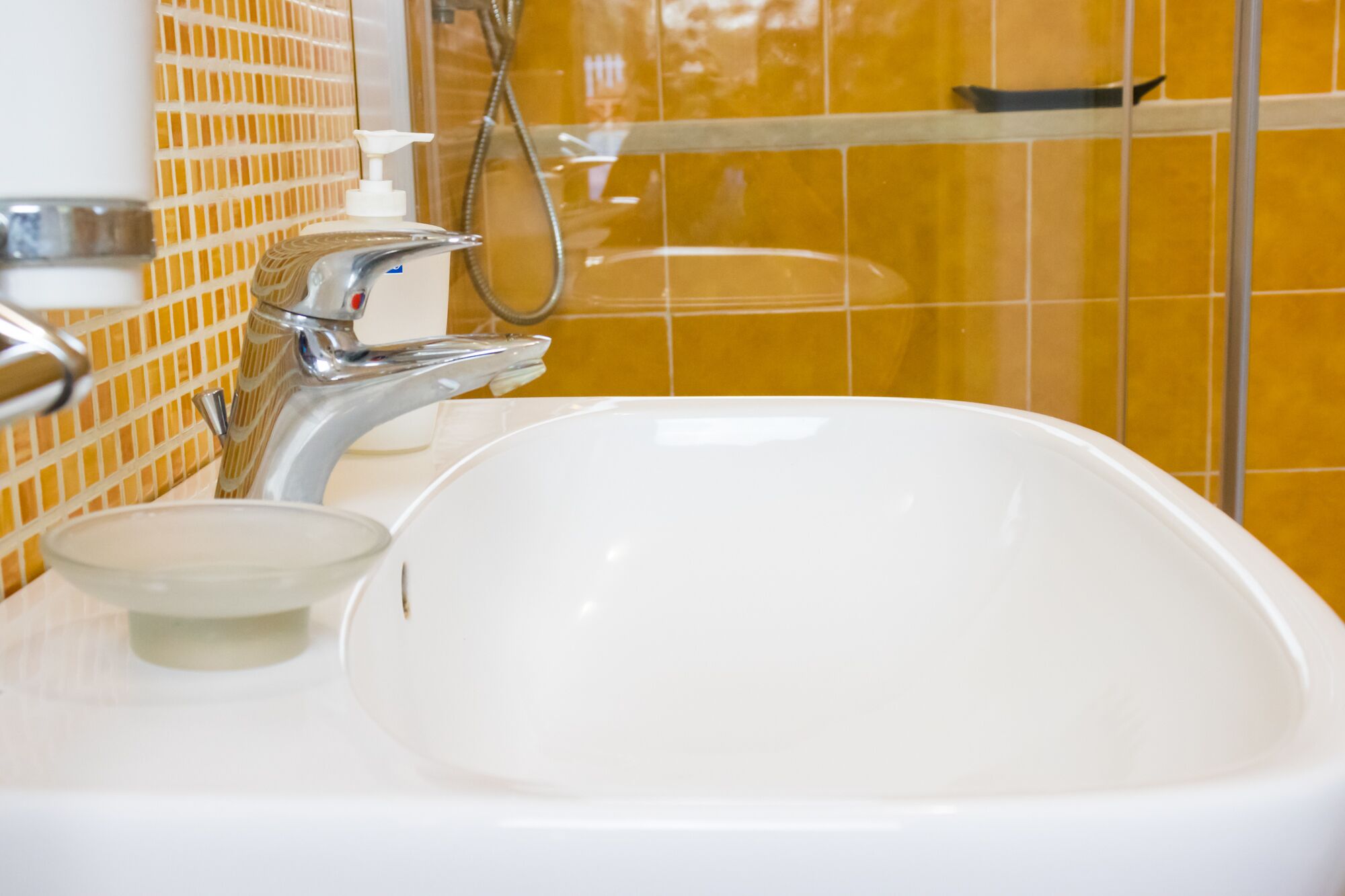 Une salle de bain avec un lavabo blanc, un robinet chromé et une douchette à main.