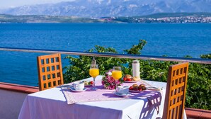 A table with breakfast items, a view of the sea, and mountains in the background.