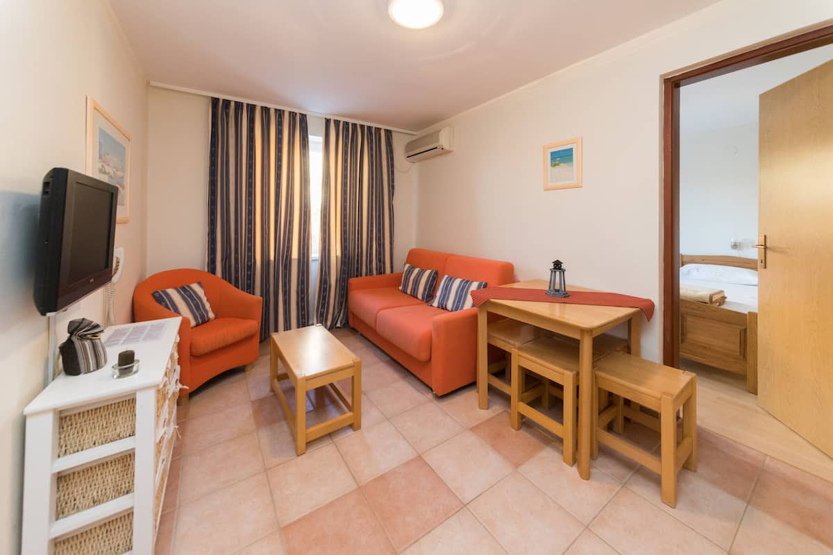 A compact living space with a sofa, a small table, a television, and a wooden door.