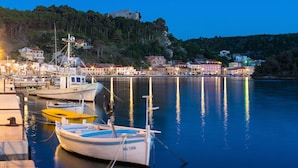 A harbor with boats docked, a lighthouse, and buildings along the waterfront.
